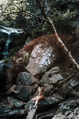 Chica joven sentada en una roca del lago