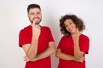 Fototapeta premium Young beautiful couple wearing red t-shirt on white background Beckoning come here gesture with hand inviting welcoming happy and smiling