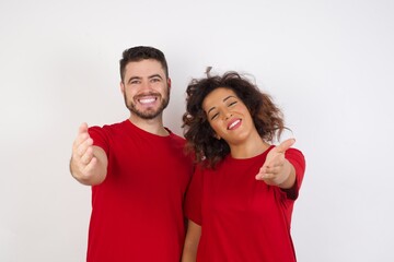 Young beautiful couple wearing red t-shirt on white background smiling friendly offering handshake as greeting and welcoming. Successful business.