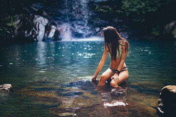 Chica en bikini en un lago con cascada tropical en una gruta verde de los arcornocales de vacaciones