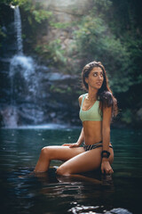 Chica en bikini en un lago con cascada tropical en una gruta verde de los arcornocales de vacaciones