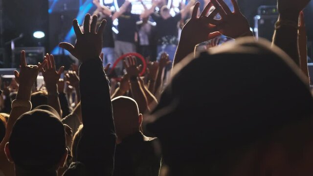 Crowd of Fans at a Rock Concert Raise their Hands Up. Slow Motion