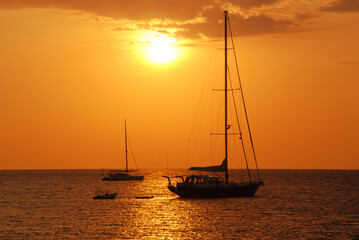 Sailboat stop on the sea at sunset and two sailboat against a vivid colorful sunset.