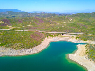 majestic aerial shot of the still blue waters and lush green hillsides at Lake Mathews in Riverside County, California