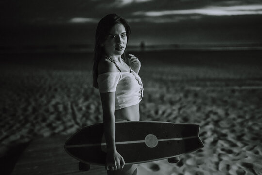 Chica veraniega morena en la playa naturaleza cañas de bambu con skateboard y bikini disfrutando de la hora dorada del atardecer