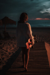 Chica veraniega morena en la playa naturaleza cañas de bambu con skateboard y bikini disfrutando de la hora dorada del atardecer