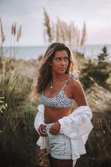 Chica veraniega morena en la playa naturaleza cañas de bambu con skateboard y bikini disfrutando de la hora dorada del atardecer