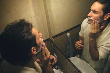 Handsome young man shaving and having his daily routine