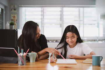 Happy mother and daughter together teaching,learning during online lesson at home. Home education concept.