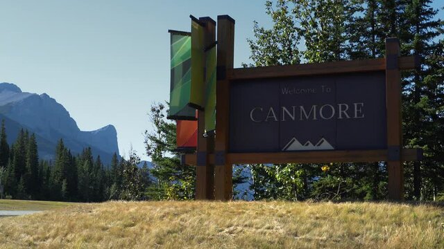 Establishing shot showing welcome sign and traffic on Trans-Canada Highway at the entrance of Canmore town during summer in Alberta, Canada.