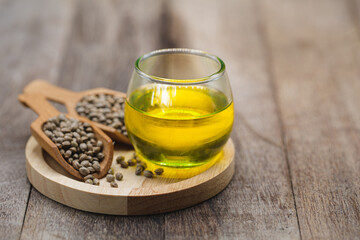 Seed hemp in a wooden spoon on the table, oil in a glass jar, CBD cannabis oil.Alternative herbs for medicine. copy space.