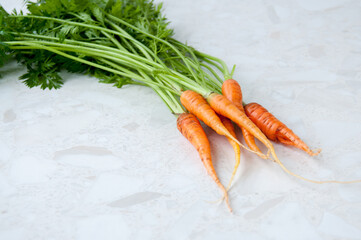 A bunch of young carrots with tops on the table, space for text