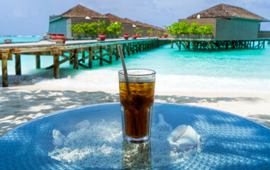 Fototapeta na wymiar A glass of cold cocktail on a table on the beach in a restaurant. Maldives