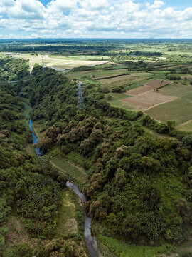 Aerial of an transmission towers running along a river gorge and undeveloped farmland in Dasmarinas Cavite.