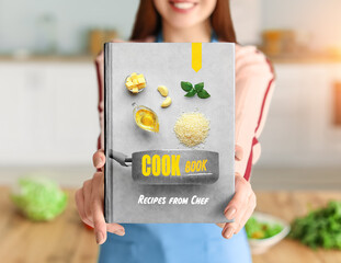 Young woman with cook book in kitchen, closeup