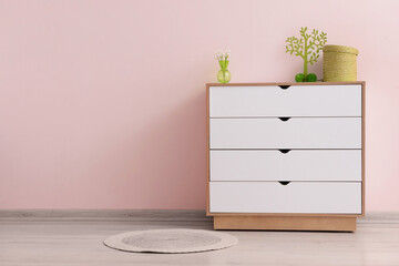 Modern chest of drawers with decor near color wall in room