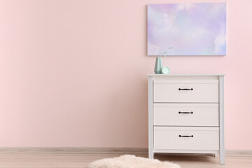 Modern chest of drawers with decor near color wall in room