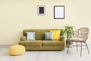 Stylish soft sofa with armchair near color wall in room
