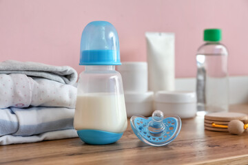 Bottle of milk for baby with pacifier on table