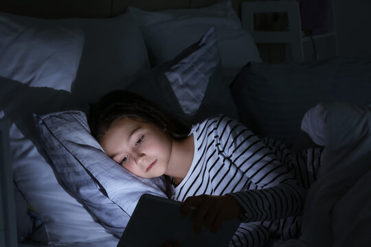 Little girl suffering from sleep disorder with tablet computer in bedroom