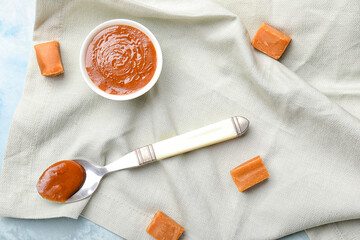 Bowl with liquid caramel and candies on table
