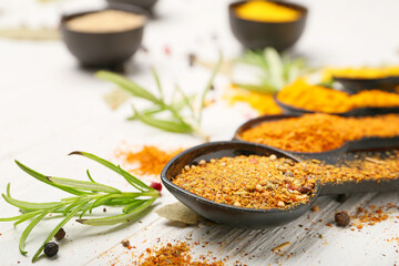 Spoons with different aromatic spices on white table
