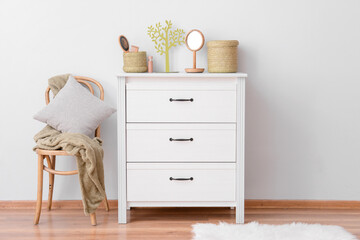 Modern chest of drawers with chair near white wall in room