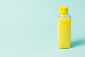 Plastic bottle with yellow detergent on a blue background.