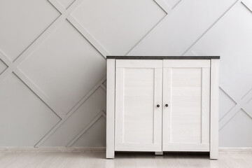 Modern chest of drawers near grey wall in room