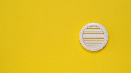 Round ventilation grille on a bright yellow background.