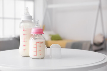 Bottles of milk for baby on table in room