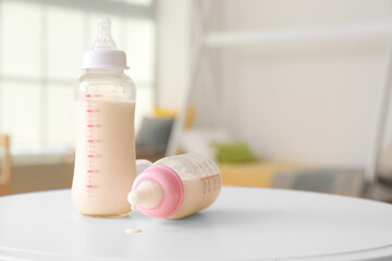 Bottles of milk for baby on table in room