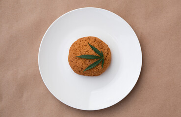 Cannabis leaf with cookies on a white plate. Cannabis live resin extraction on kraft background. Medical marijuana concept