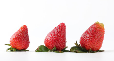 Three fresh strawberries in a row on white background.
