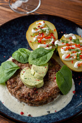 Close up of grilled meat fritter with baked potato and creamy sauce, dressed with aroma herbal butter