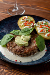 Close up of grilled meat fritter with baked potato and creamy sauce, dressed with aroma herbal butter