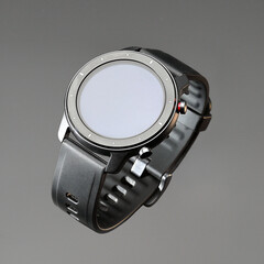 Wireless smart watch in a round matte black case with risks on the rim and a silicone strap on a gray background.