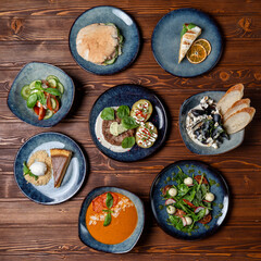 Circle of plates on the table, buffet in a restaurant, assorted european meals on wooden background