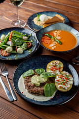 Above view of european lunch on wooden table: gazpacho, meat patty, salad and dessert