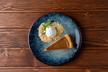 Chocolate tart with cookie crumbs and a scoop of vanilla ice cream top view on a wooden restaurant table