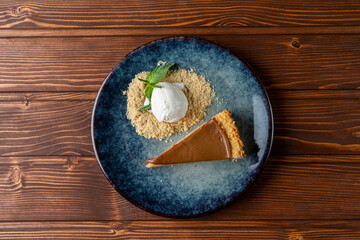 Chocolate tart with cookie crumbs and a scoop of vanilla ice cream top view on a wooden restaurant table