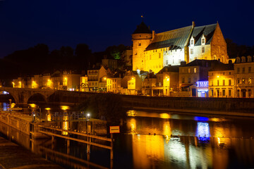 Fototapeta na wymiar Night view across Mayenne river of French town of Laval overlooking illuminated medieval Chateau in summer