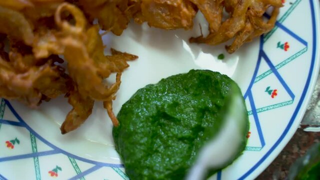 Putting Mint Sauce At The Side Of Fried Onion (Onion Pakoda) On A Plate In India. - Close Up Shot