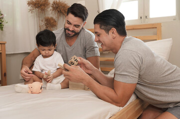 Young married LGBT parent couples play with adopted child in bedroom