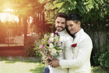 Young married LGBT couples celebrate a romantic wedding ceremony together with a bouquet flower in a suit