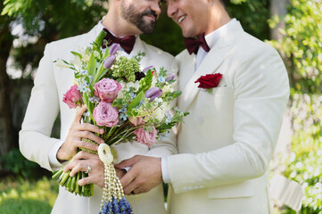 Young married LGBT couples celebrate a romantic wedding ceremony together with a bouquet flower in a suit - Powered by Adobe