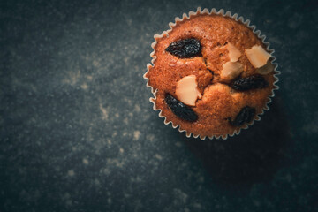banana cupcake with almond slice and raisin compose on a dark black kitchen table