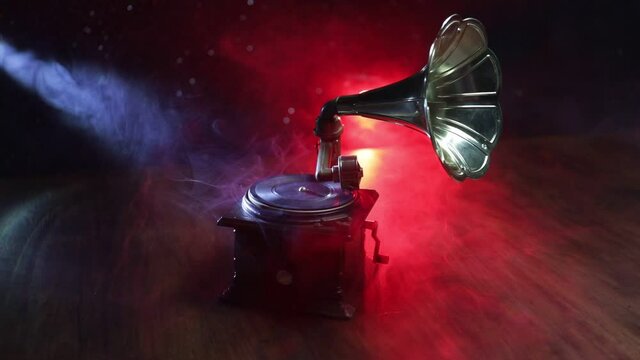 Music concept. Old gramophone on a dark background. Retro gramophone with disc on wooden table with toned backlight. Slider shot
