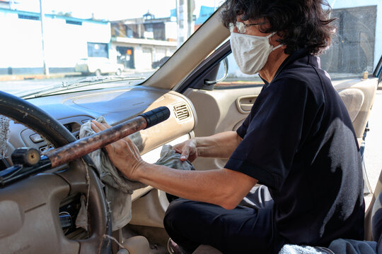 man with face mask cleaning his car