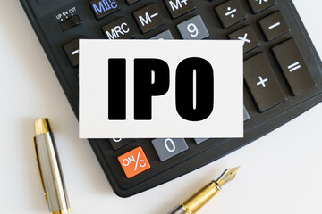 On the table there is a pen, a calculator and a business card on which the text is written IPO. INITIAL PUBLIC OFFERING